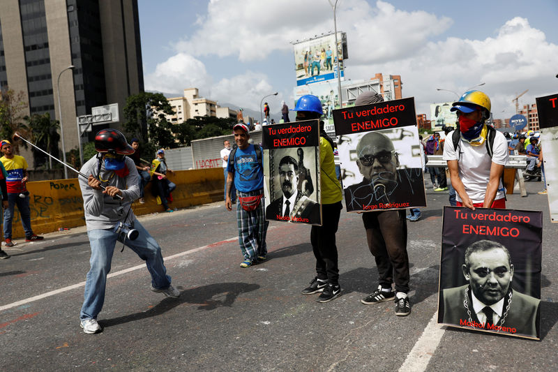 © Reuters. Demonstrators carry signs with images of President Maduro and politician Rodriguez and judge Moreno that reads "your real enemy" while rallying against President Nicolas Maduro in Caracas