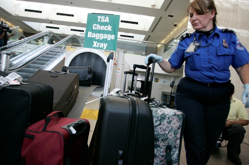 © Reuters. FILE PHOTO - TSA worker loads suitcases at luggage security screening station at Los Angeles International Airport