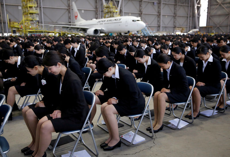 © Reuters. FILE PHOTO: Newly-hired employees of JAL group bow during an initiation ceremony at a hangar of Haneda airport in Tokyo