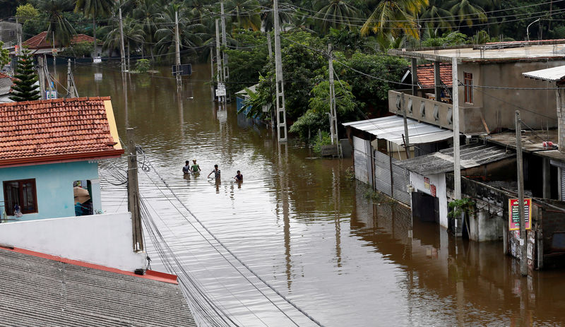 © Reuters. A group of men walk through a flooded road during a rescue mission in Nagoda village in Kalutara, Sri Lanka