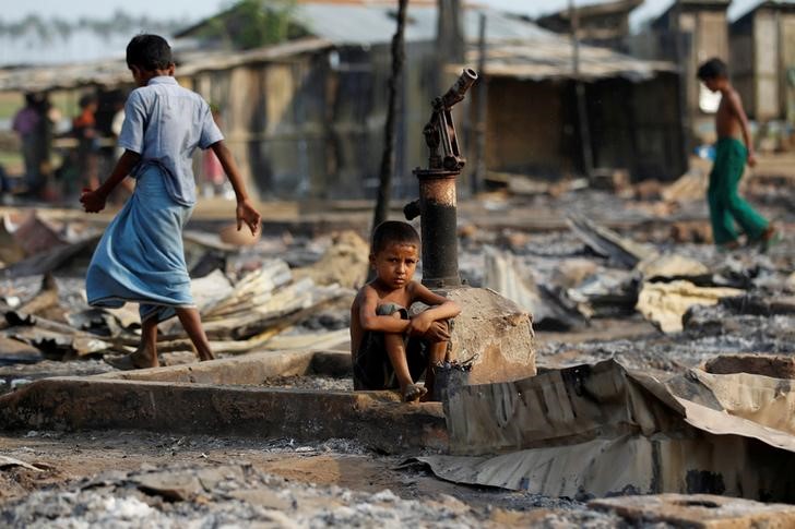 © Reuters. FILE PHOTO: A boy sit in a burnt area after fire destroyed shelters at a camp for internally displaced Rohingya Muslims in the western Rakhine State near Sittwe