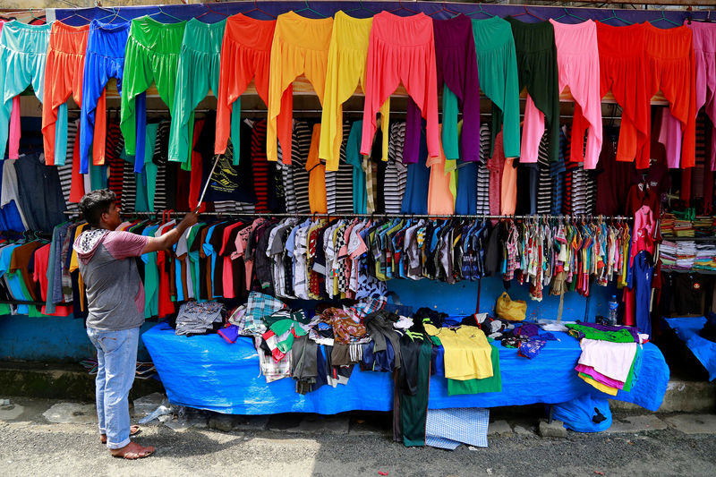 © Reuters. FILE PHOTO: A vendor arranges clothes at his roadside shop in Kochi