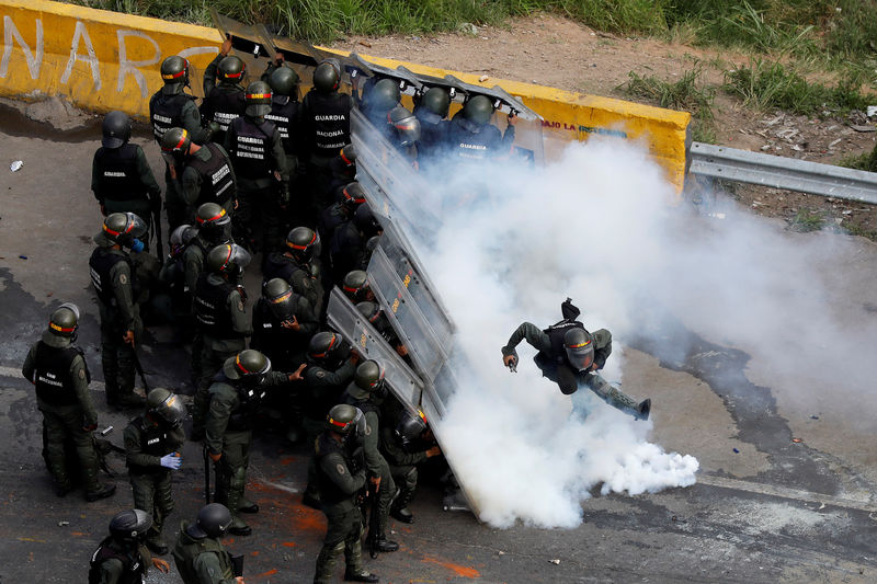 © Reuters. Membro das forças de segurança chuta recipiente de gás lacrimogêneo durante protesto em Caracas, Venezuela