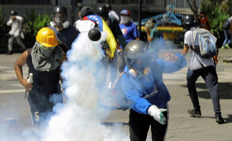 © Reuters. A demonstrator throws a tear gas canister during clashes with riot security forces at a protest against Venezuelan President Nicolas Maduro's government in Caracas