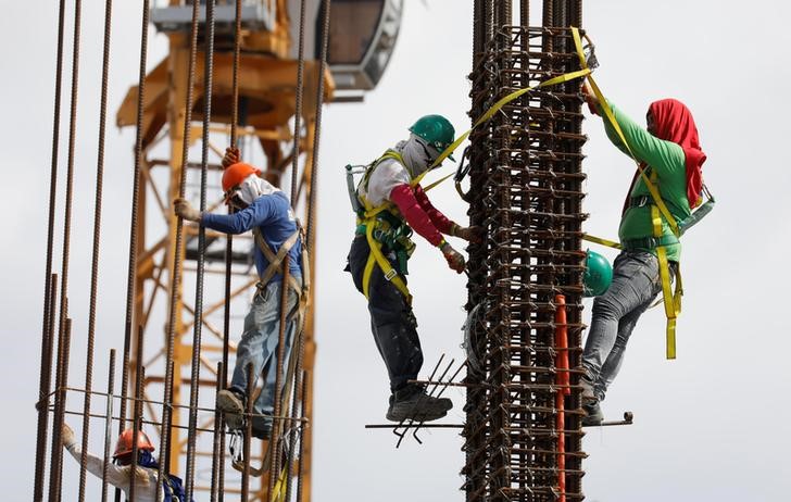 © Reuters. Construction workers are pictured at the construction site of an apartment building in Pasay