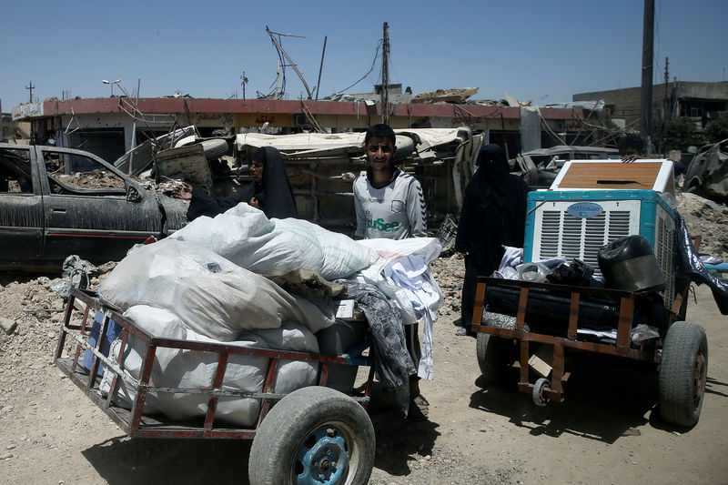 © Reuters. Displaced Iraqi people carry their belongings as they flee from western Mosul