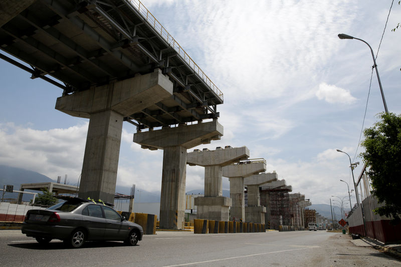 © Reuters. Commuters drive past a construction site by Odebrecht of the Caracas - Guatire metro rail project in Guatire