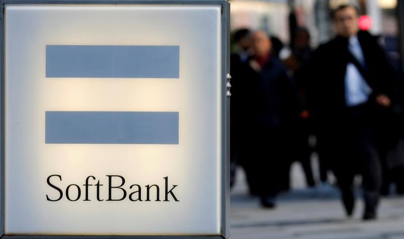 © Reuters. FILE PHOTO -  People walk behind the logo of SoftBank Corp in Tokyo