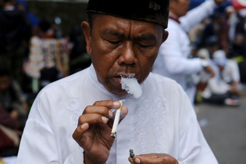 © Reuters. An Indonesian man smokes a cigarette during a protest near South Jakarta court in Jakarta