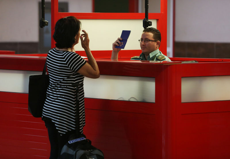 © Reuters. A Cuban immigration official checks the passport of a Cuban national before she boards her flight at the Jose Marti International Airport in Havana