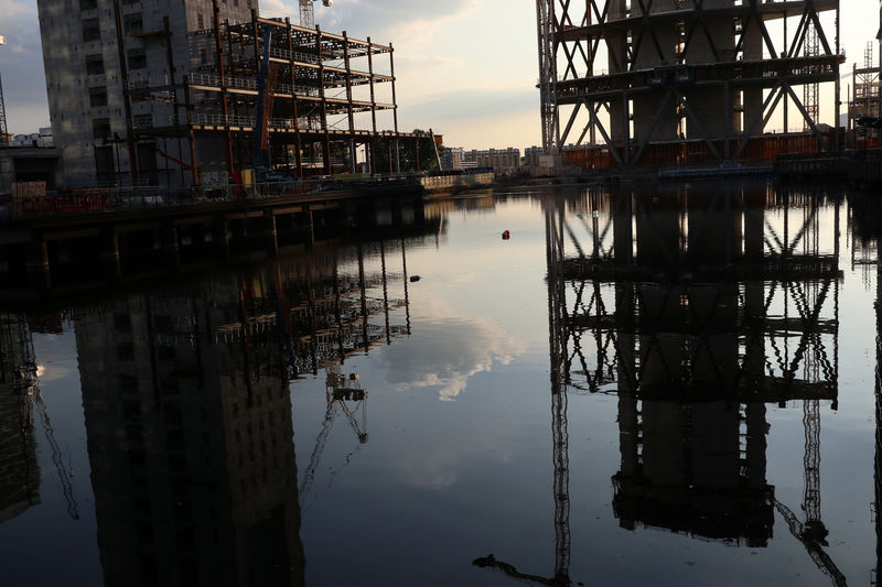 © Reuters. Construction work is reflected in a canal in London's Financial centre at Canary Wharf In London