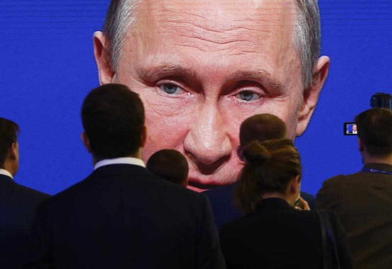 © Reuters. Participants of the St. Petersburg International Economic Forum gather near an electronic screen showing Russian President Putin during a session of the forum in St. Petersburg