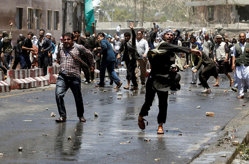 © Reuters. Afghans throw stones towards security forces during a protest in Kabul