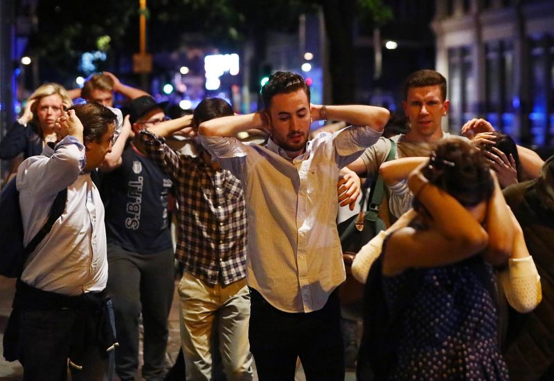 © Reuters. People leave the area with their hands up after an incident near London Bridge in London