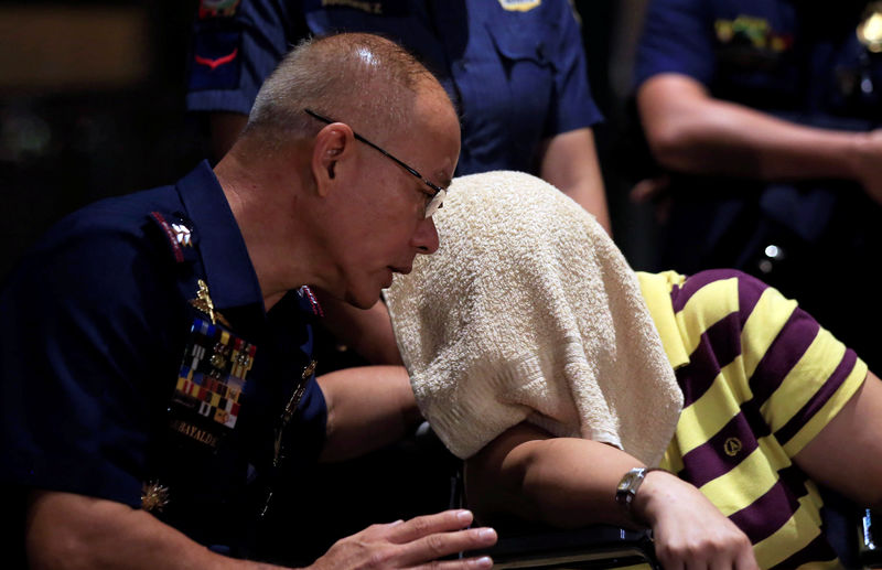 © Reuters. Oscar Albayalde, chief of the capital's police office, talks to the wife of gunman Jessie Javier Carlos during a press briefing at a hotel in Pasay city, metro Manila