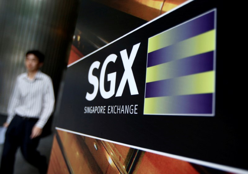 © Reuters. An office worker walks past a logo of SGX outside its premises in Singapore