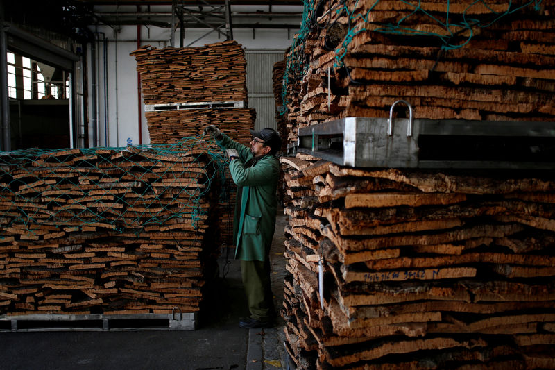 © Reuters. FILE PHOTO: A man places a net over a pallet with cork in Amorim Revestimentos factory unit in Sao Paio de Oleiros