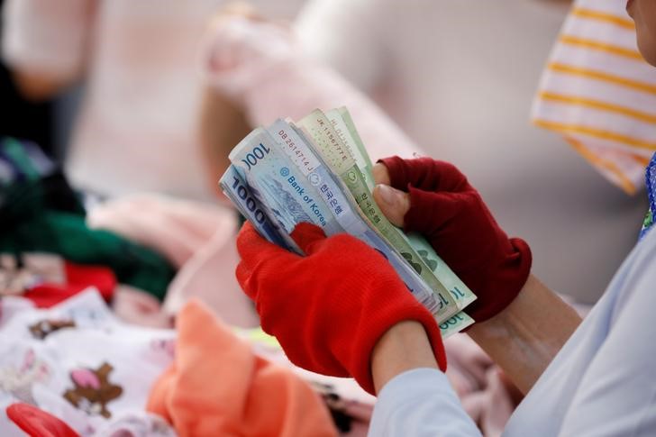 © Reuters. A street vendor counts his money at the Namdaemun Market in Seoul