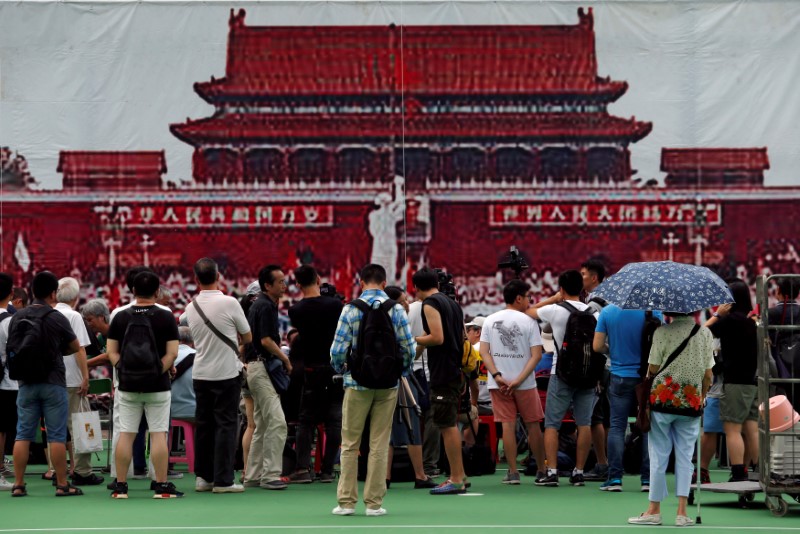 © Reuters. People stand in front of a a banner featuring a scene at Beijing's Tiananmen Square in 1989, in Hong Kong