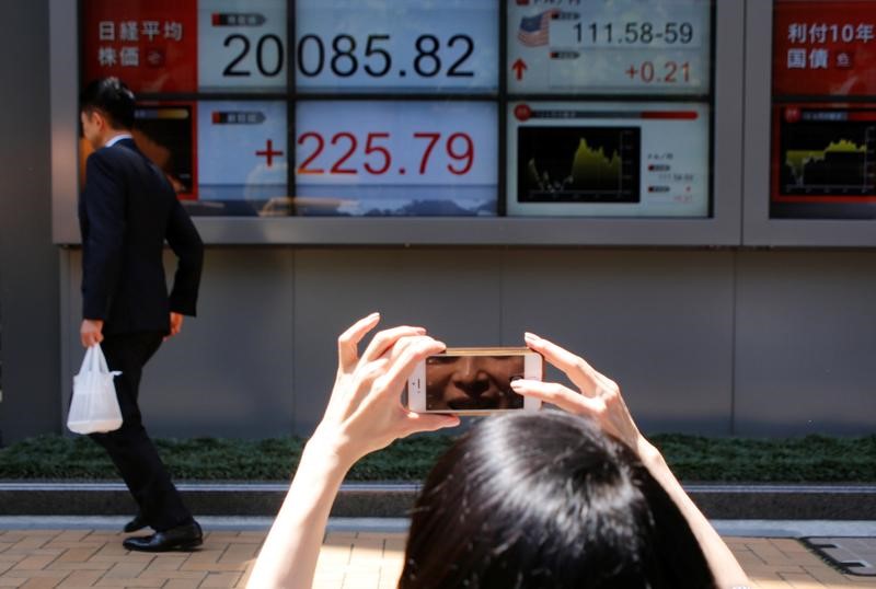 © Reuters. A woman takes a photo of an electronic board showing Japan's Nikkei average outside a brokerage in Tokyo