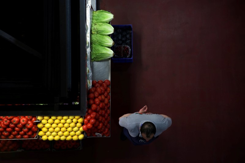© Reuters. FILE PHOTO: A grocer waits for customers next to his stand at a food market in Madrid