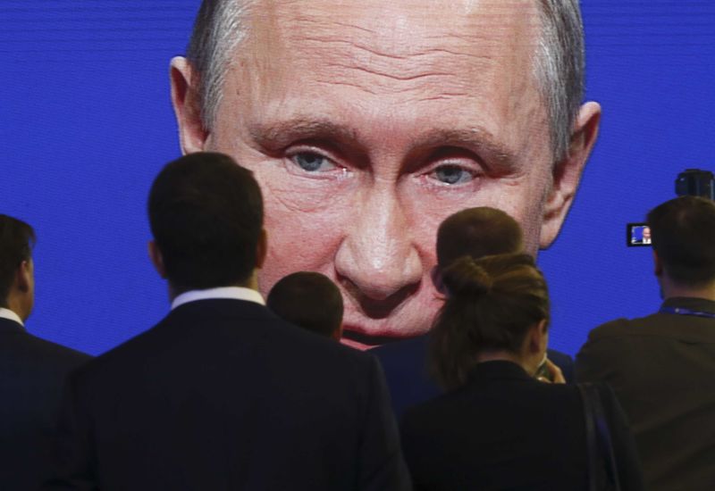 © Reuters. FILE PHOTO: Participants of the St. Petersburg International Economic Forum gather near an electronic screen showing Russian President Putin during a session of the forum in St. Petersburg