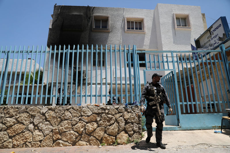 © Reuters. An Israeli policeman patrols in front of a police station that police said, was stormed by hundreds of protesters during clashes which erupted overnight, in the Arab town of Kafr Qassem