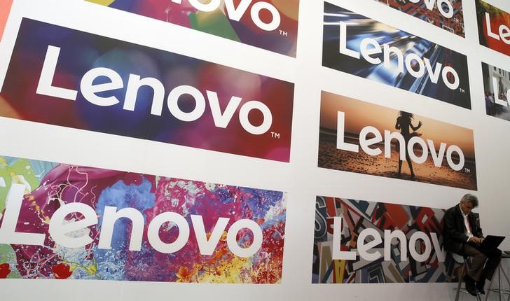 © Reuters. A man uses his laptop next to Lenovo's logos during the Mobile World Congress in Barcelona