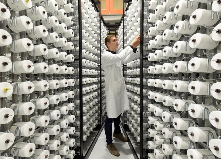 © Reuters. An employee checks spools of plastic fibre in a giant loom at the Open Hybrid Lab Factory, which is a research and development center of several companies like German car maker Volkswagen, in Wolfsburg