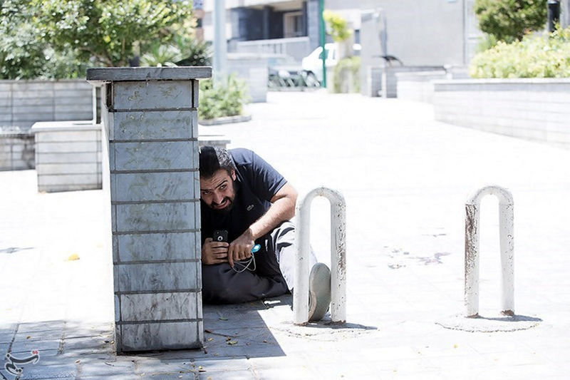 © Reuters. A man takes cover during an attack on the Iranian parliament in central Tehran