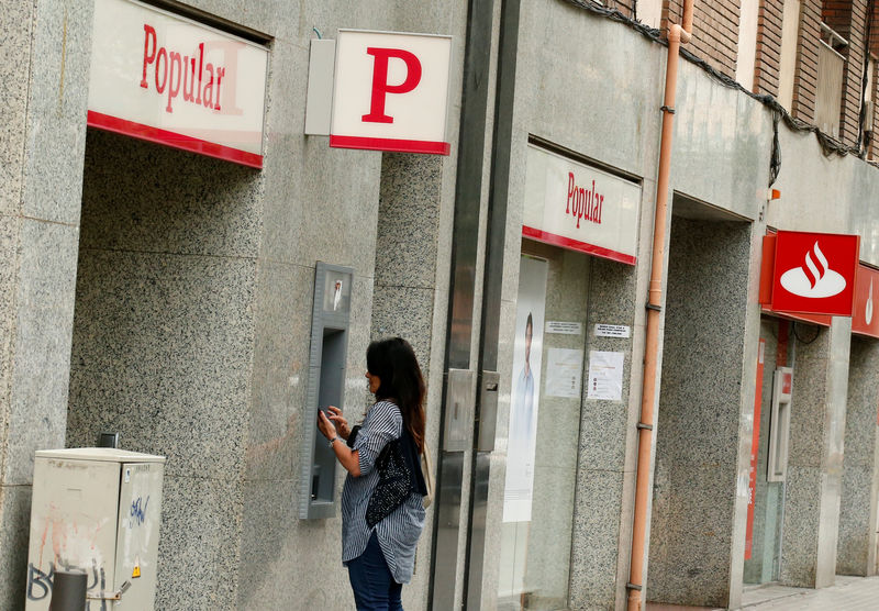 © Reuters. Mulher usa caixa eletrônico do Banco Popular ao lado de um escritório do Santander, em Barcelona