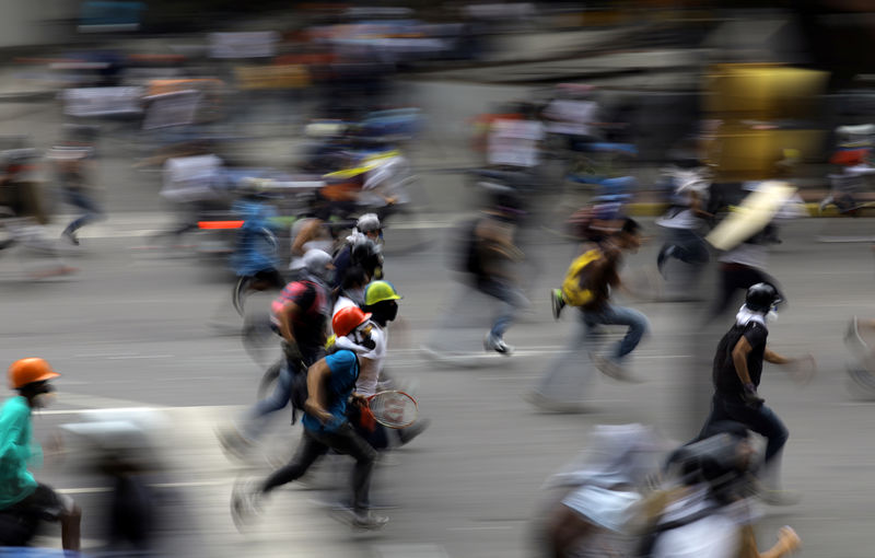 © Reuters. Manifestantes correm durante confronto com forças de segurança em protesto contra o presidente da Venezuela, Nicolás Maduro, em Caracas