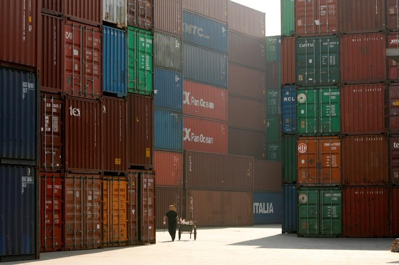 © Reuters. FILE PHOTO: Woman walks past containers at port in Shanghai