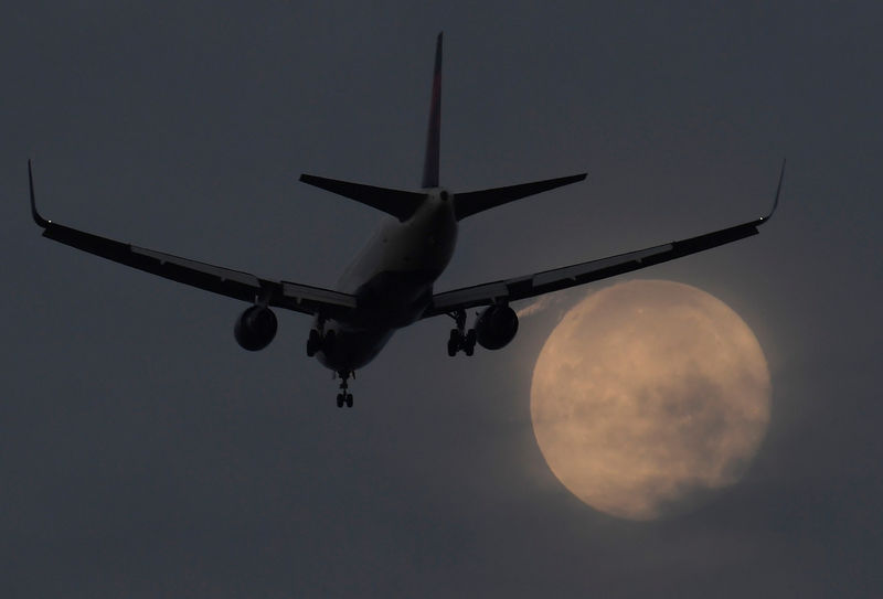 © Reuters. FILE PHOTO: A passenger aircraft makes it's landing approach to Heathrow airport in front of a "super moon" at dawn in west London