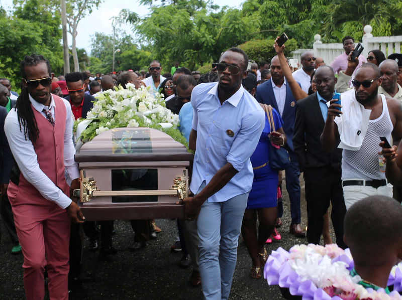 © Reuters. Jamaica's Olympic champion Usain Bolt carries the coffin of high jump star Germaine Mason, who died in a motorbike crash, to the cemetery in Grange Hill, Portland