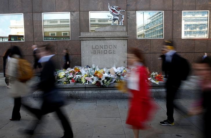 © Reuters. Commuters walk past floral tributes to the victims of the recent attack at London Bridge and Borough Market in central London