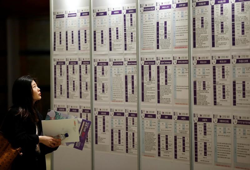 © Reuters. A woman looks at recruiting information during a job fair in Seoul