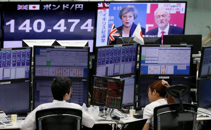 © Reuters. Employees of a foreign exchange trading company work near monitors showing TV news on Britain's general election and the Japanese yen's exchange rate against British pound in Tokyo