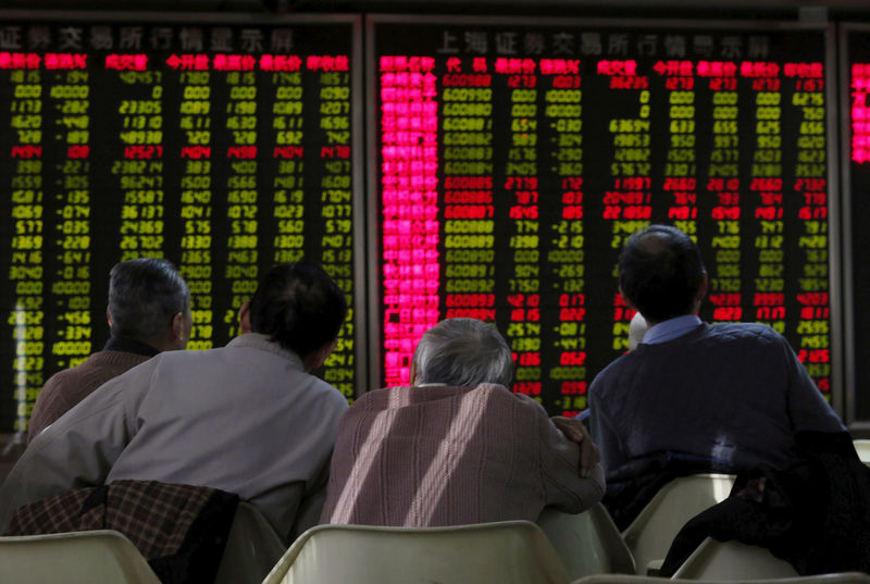 © Reuters. FILE PHOTO: Men look at electronic board showing stock market information at a brokerage house in Beijing