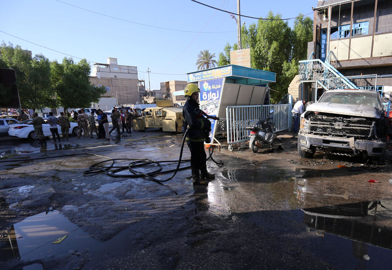 © Reuters. Bombeiro limpa rua após ataque com bombas na cidade de Kerbala, no Iraque