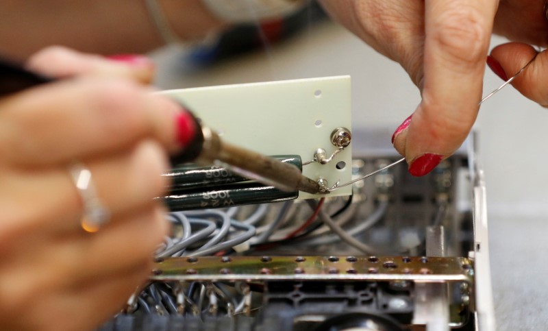 © Reuters. FILE PHOTO: A worker uses a soldering iron at the Mec Com Ltd factory near Stafford, central England.