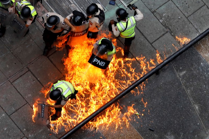 © Reuters. Riot security forces members catch fire during riots at a rally against Venezuelan President Nicolas Maduro's government in Caracas,