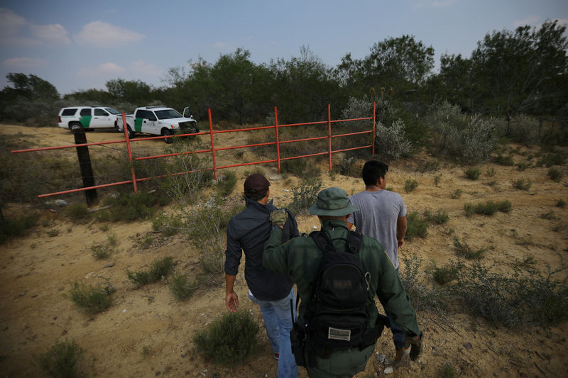 © Reuters. FILE PHOTO - A U.S. border patrol agent escorts men being detained after entering the United States by crossing the Rio Grande river from Mexico in Roma