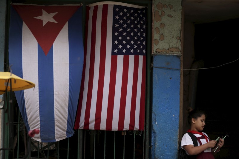 © Reuters. A child is seen in front of a house adorned with flags of U.S. and Cuba on the outskirts of Havana