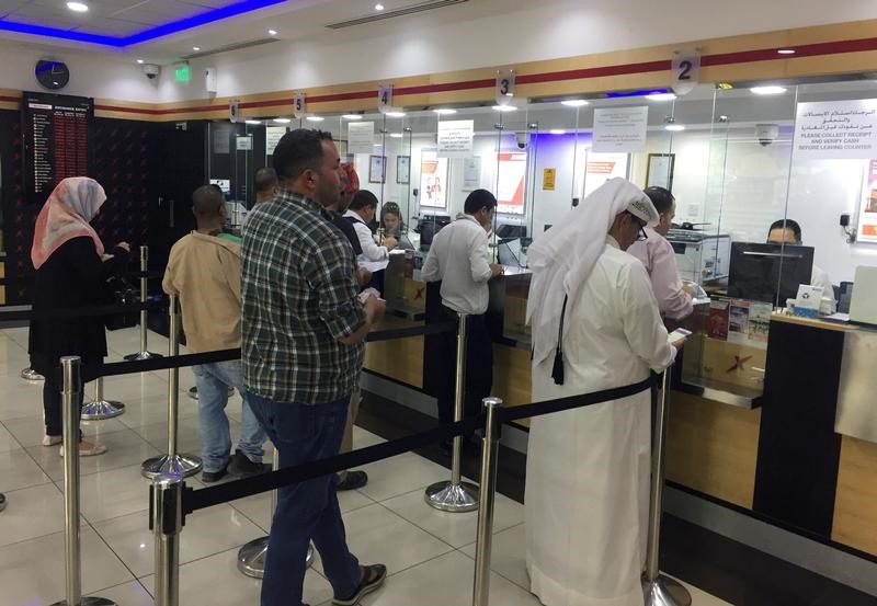 © Reuters. People exchange money at a money exchange office in Doha