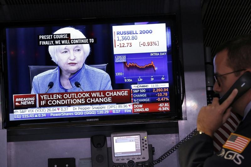 © Reuters. A trader works on the floor of the New York Stock Exchange as a television screen displays coverage of U.S. Federal Reserve Chairman Janet Yellen shortly after the announcement that the U.S. Federal Reserve will hike interest rates, in New York