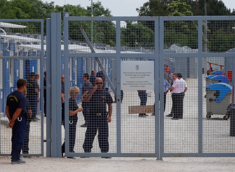 © Reuters. Security guards stand by the gate of the transit zone where migrants are hosted in container camps and their asylum claims are processed, in Tompa