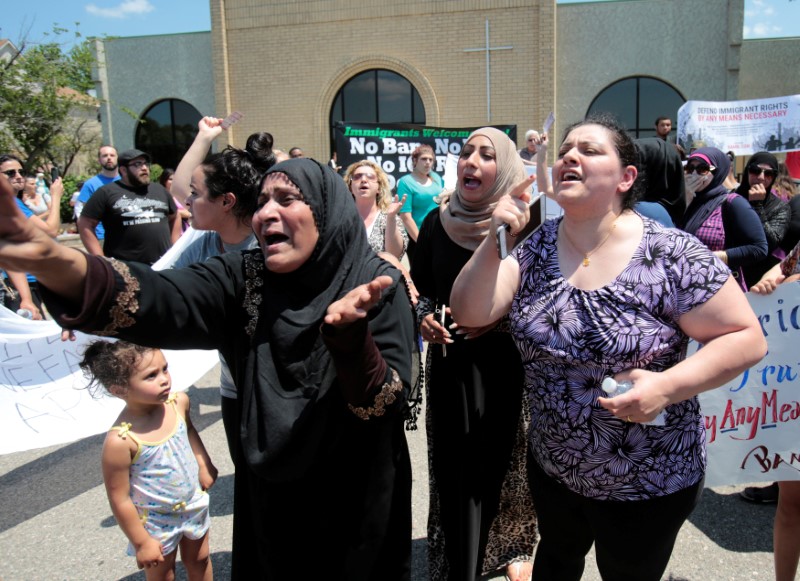 © Reuters. A group of women react as they talk about family members seized on Sunday by Immigration and Customs Enforcement agents during a rally outside the Mother of God Catholic Chaldean church in Southfield