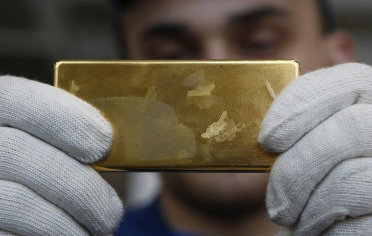 © Reuters. Рабочий держит слиток золота