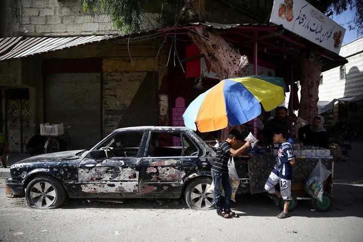 © Reuters. Children buy snacks from a cart vendor in the rebel held besieged city of Douma, in the eastern Damascus suburb of Ghouta